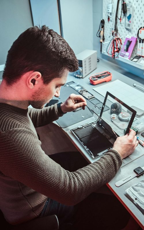 The technician repairs a broken tablet computer in a repair shop